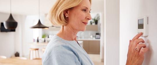 woman adjusting thermostat