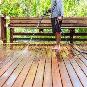 Person power washing their wooden deck